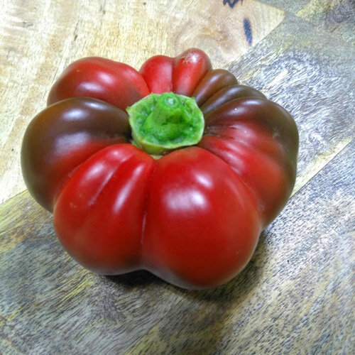 Peperone a pomodoro rosso e costoluto su un tavolo di legno