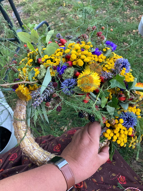 Ghirlanda autunnale a metà con fiori gialli e blu, erbe e bacche su base di paglia
