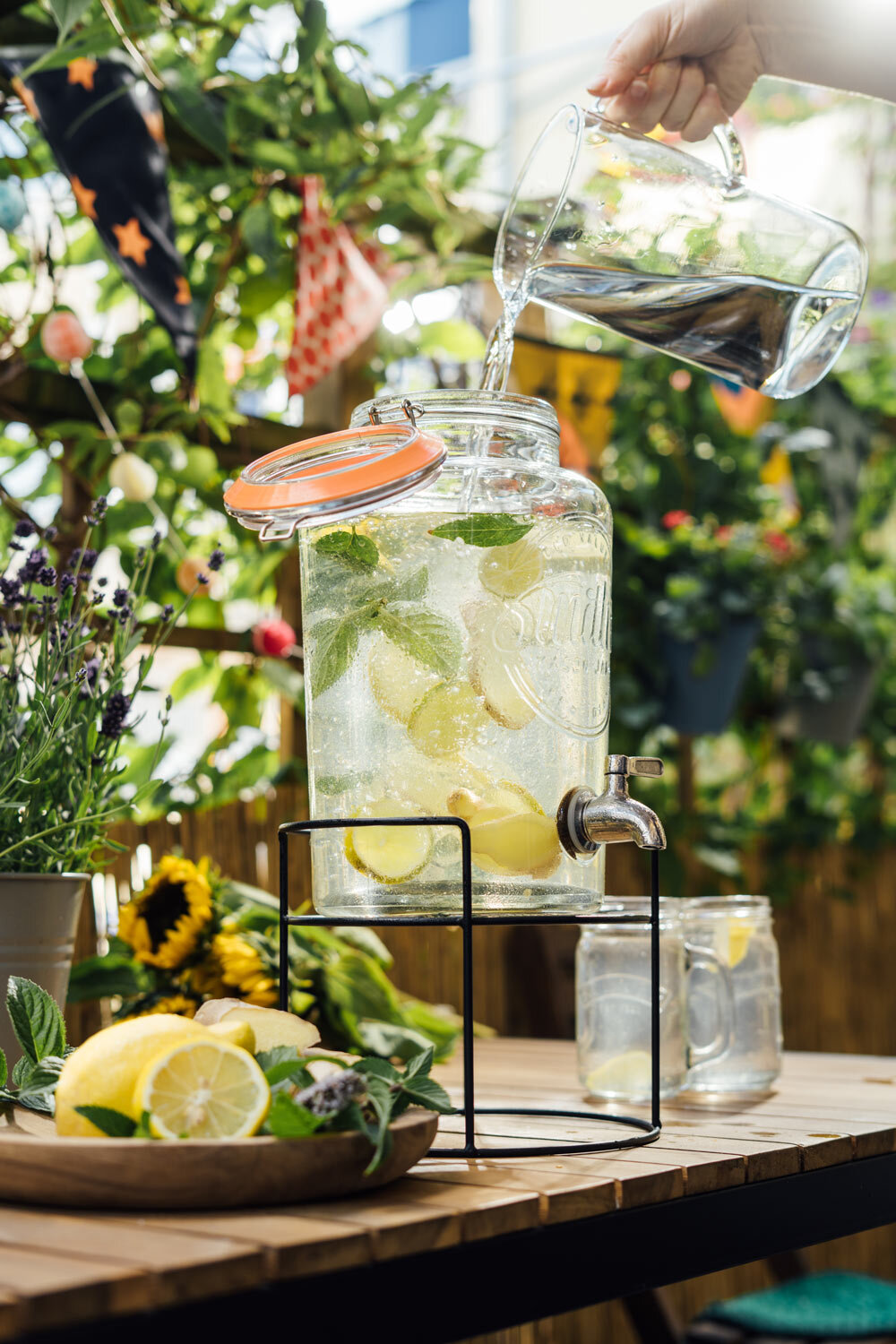 Acqua versata in un dispenser con limone e menta, limonata fatta in casa sul balcone