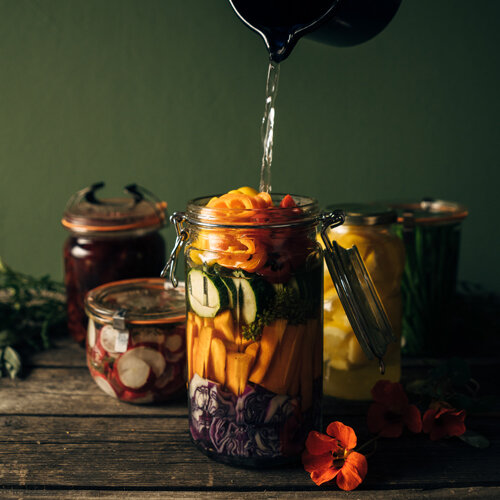 Verdure da fermentare: carote, zucchine e cavolo rosso in un barattolo, coperti di salamoia